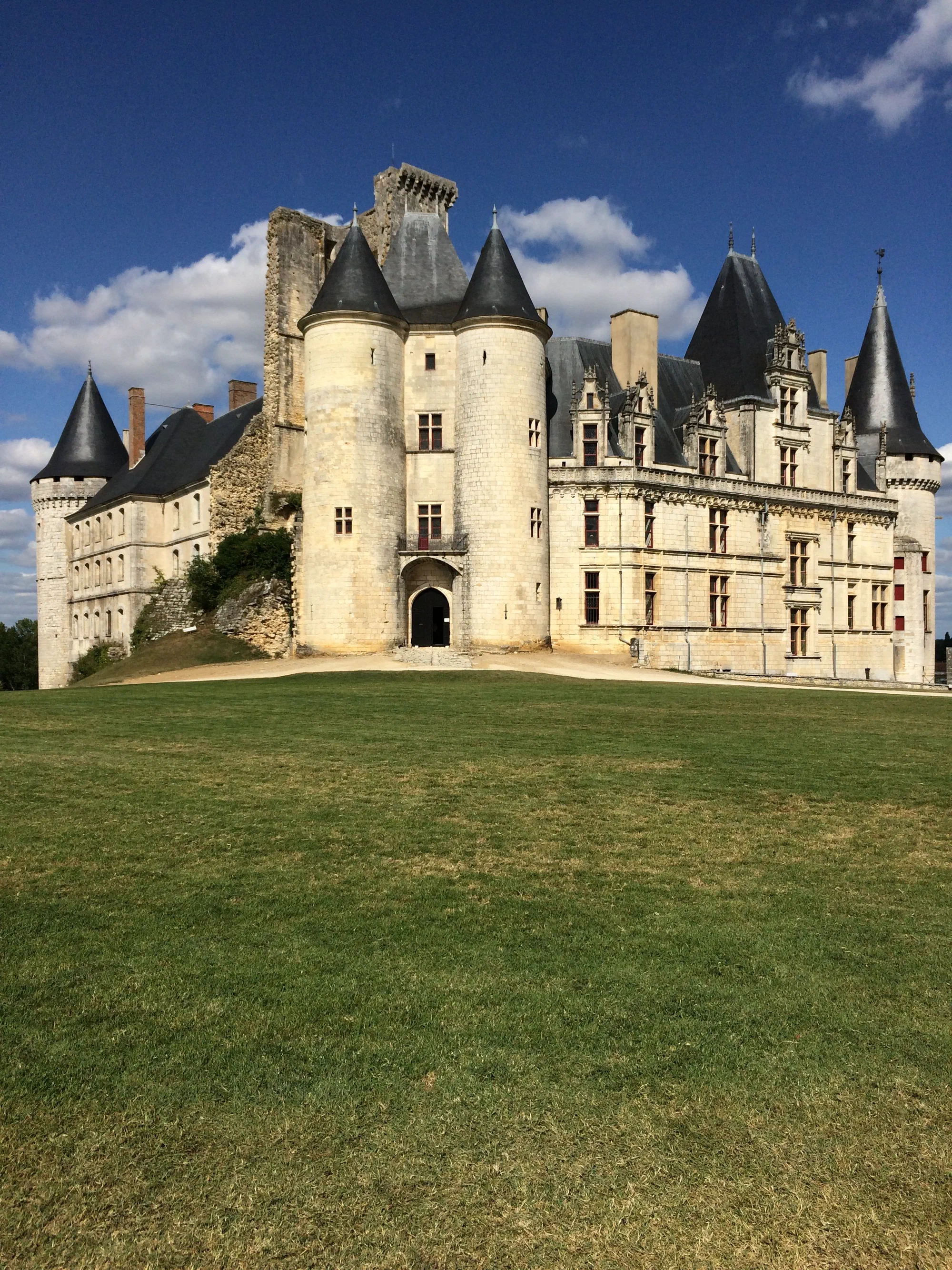 Le château de La Rochefoucauld, son donjon roman et son aile Renaissance aux toits d'ardoise, vus depuis la pelouse