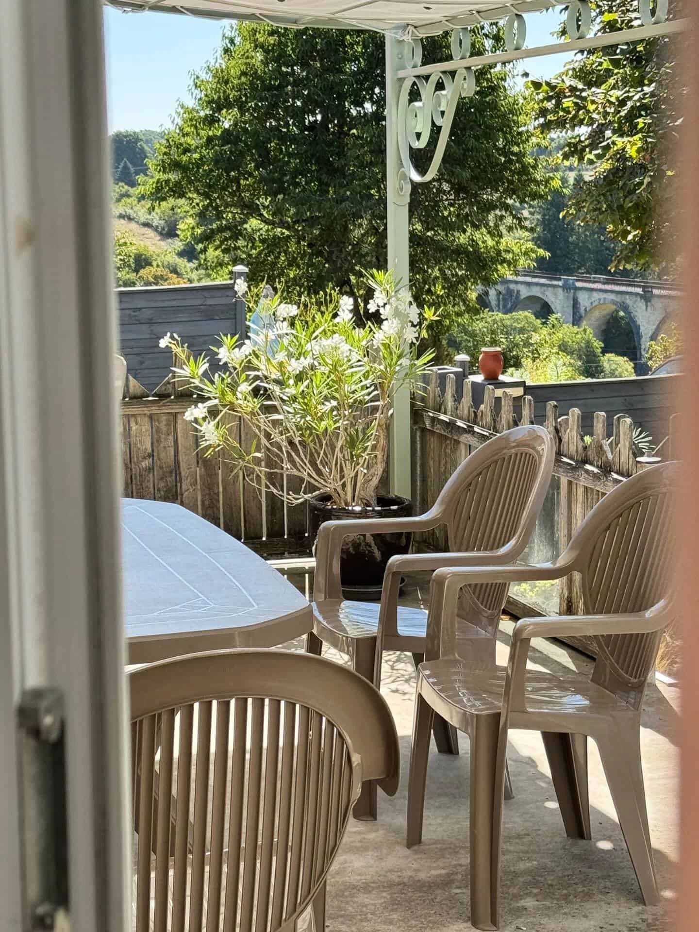 La terrasse couverte, avec sa table et ses fauteuils, ouverte sur le viaduc