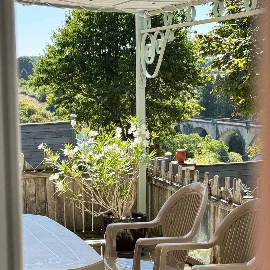 La terrasse couverte, avec sa table et ses fauteuils, ouverte sur le viaduc